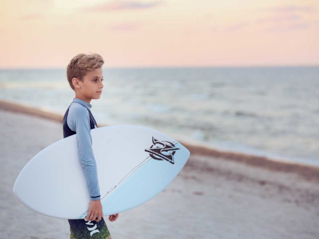 Boy with surfboard at Sunny Isles Beach