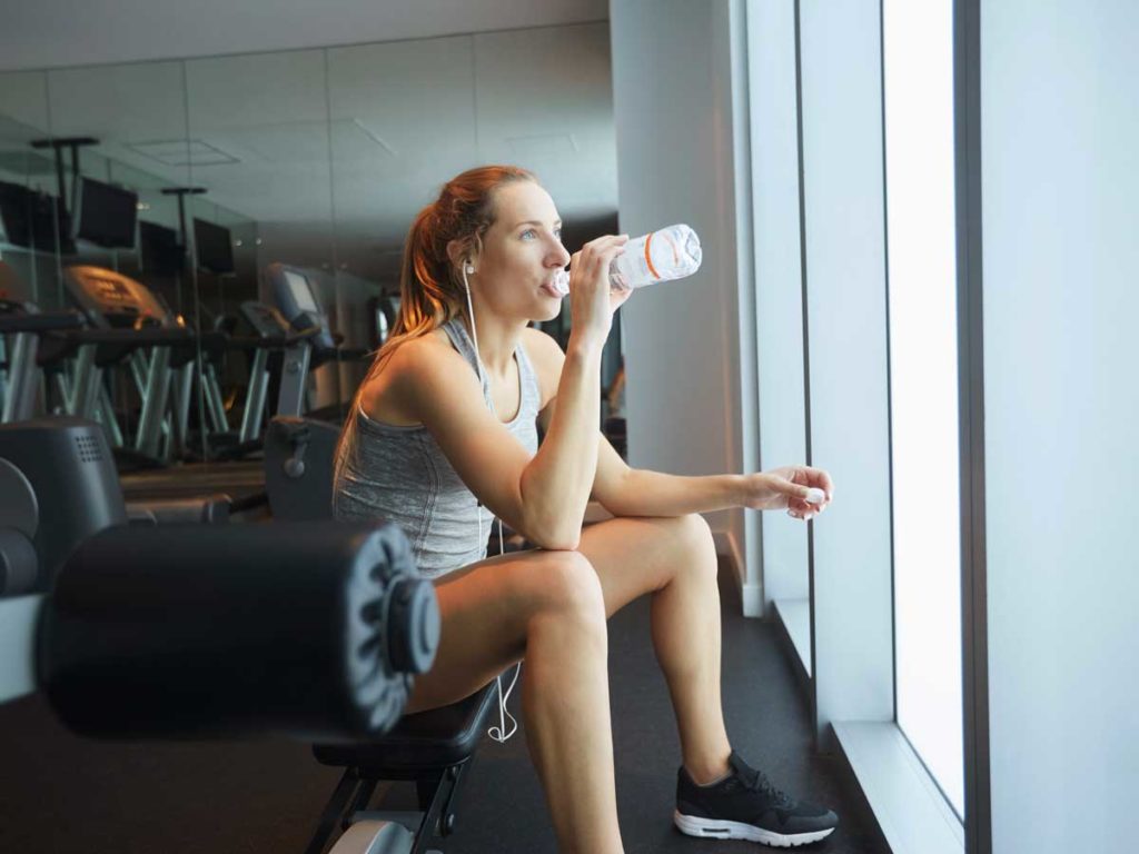 Woman drinking water at a gym, in Sunny Isles Beach