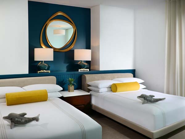 Double Queen Bed Guestroom With Stuffed Dolphins.