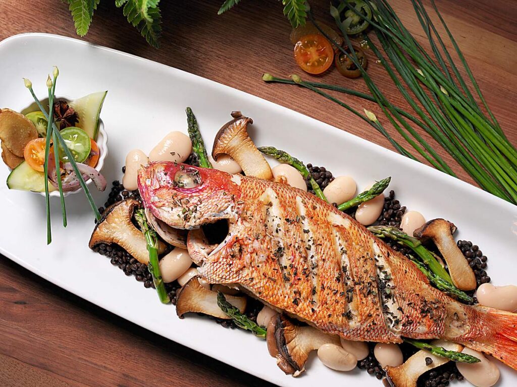 Whole roasted red snapper with asparagus, mushrooms, and beans at BALEEN Kitchen, the waterfront restaurant at Sole Miami Resort in Sunny Isles Beach