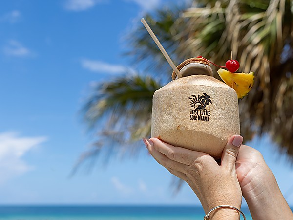 Fresh coconut cocktail with pineapple and cherry garnish at Tipsy Turtle beach bar, Sole Miami oceanfront resort, Sunny Isles Beach