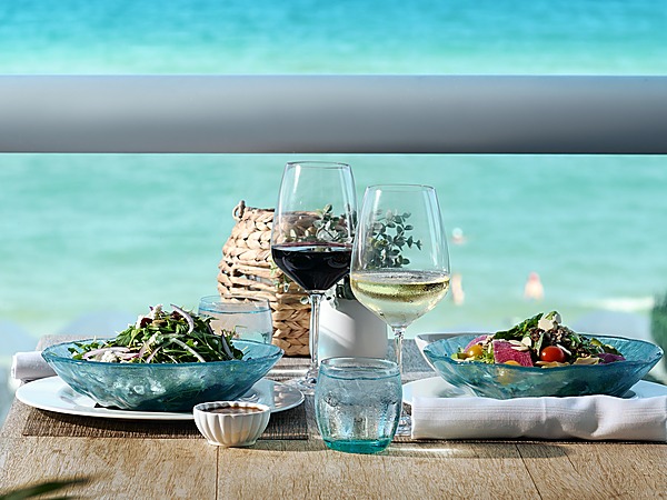 Two fresh garden salads with red and white wine on an oceanfront verandah table at BALEEN Kitchen, Sole Miami resort in Sunny Isles Beach